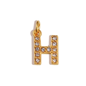 Macro view of gold H letter pendant with sparkling crystals on white background