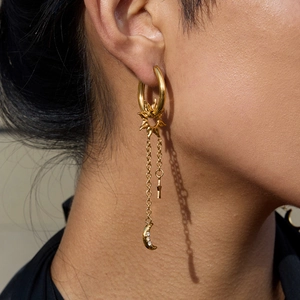 Boucles d'oreilles dorées avec breloques soleil lune et étoile vues de profil élégamment
