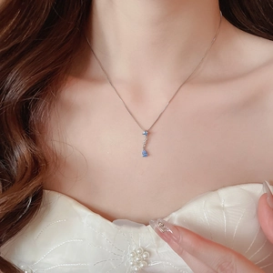 Detail view of silver necklace with blue water-drop gemstone pendant on model