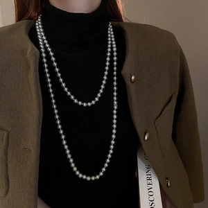 Detail of long layered grey pearl necklace with lustrous finish on a dark wool coat