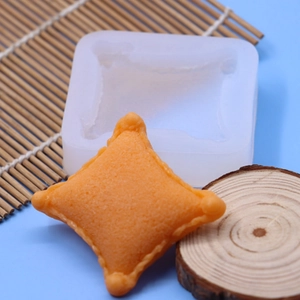 White silicone pillow shape fondant mold with orange cushion finish on blue background