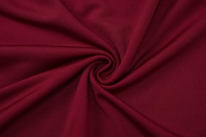 Close-up of red knit fabric with spiral texture and soft sheen for backless dress