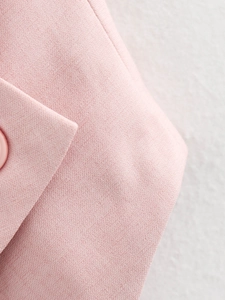 Detail of pink twill fabric and matching resin button on an asymmetric women vest