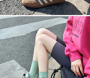 Detail of light blue crew socks with contrast embroidery worn with grey cycling shorts