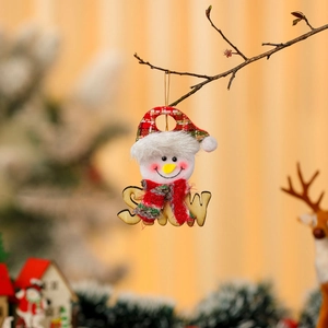 Macro shot of snowman plush pendant with SNOW wood plaque hanging on a rustic branch