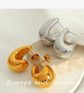 Detail showing polished gold and silver teardrop earrings on textured stone background