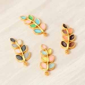 Macro detail of leaf-shaped stainless steel charms in assorted colorful enamel finishes