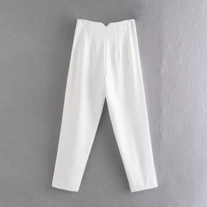 Dettaglio dei pantaloni bianchi a vita alta con taglio a V e design a pieghe in vita