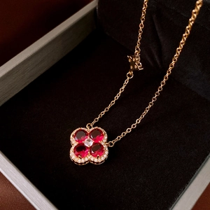 Macro view of gold four-leaf flower pendant with red zircons and fine micro-pave diamonds
