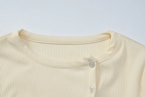 Detail of the knit ribbed neckline and transparent buttons on the beige cardigan