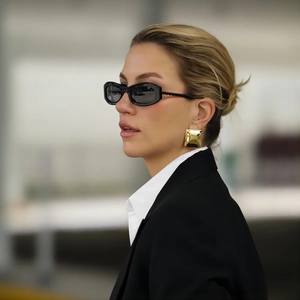 Chic model wearing black rectangle sunglasses with gold textured square stud earrings
