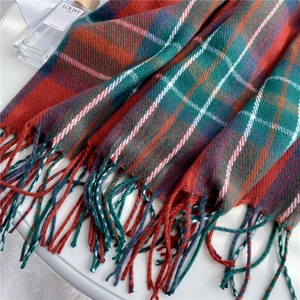 Close-up of soft red and green plaid scarf texture with stylish fringe details
