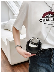 Close-up of mini black patent leather crossbody bag with silver handle and chain strap