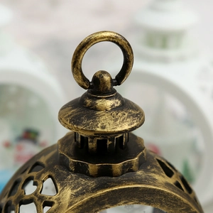 Close-up of vintage bronze lantern top featuring a round handle and ornate cutout patterns