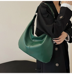 Detail der dunkelgrünen Hobo-Tasche aus Leder mit Litschi-Muster und schwarzem Blazer