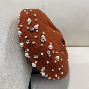 Detail of caramel wool beret featuring elegant faux pearl and rhinestone embellishments