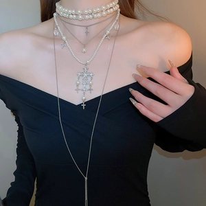 Close-up of layered necklace set featuring a pearl choker and a cross pendant on model