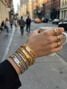 Close-up of stacked gold and silver Cuban chain bracelets with a screw design bangle