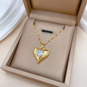 Luxurious gold heart pendant necklace with shimmering crystals in a beige jewelry box