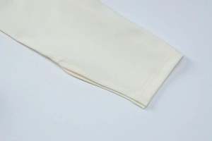 Detail des cremefarbenen Strickkleid-Ärmels mit Daumenlöchern und feiner Verarbeitungsqualität