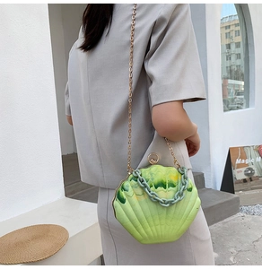 Detail of light green shell-shaped acrylic handbag with gold and resin chain straps