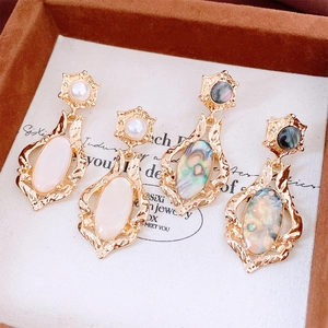 Detailed close-up of retro hollow oval earrings with shell inlays in a velvet box