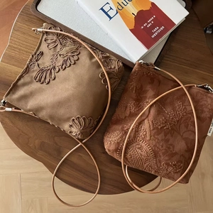 Détail de la broderie florale sur les sacs bandoulière en daim camel et marron