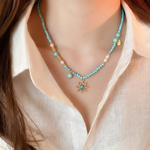 Gros plan du collier pendentif soleil avec perles d'eau douce et perles turquoise sur mannequin