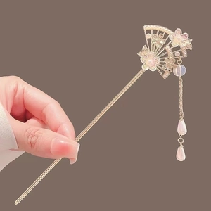 Close-up of a fan-shaped metal hair stick with magnolia flower and pearl tassels