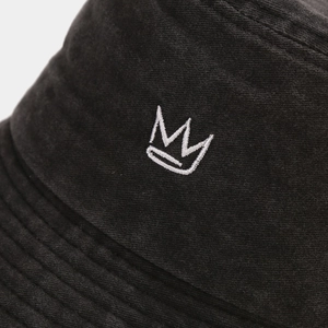 Close-up of white crown embroidery on washed black cotton vintage bucket hat