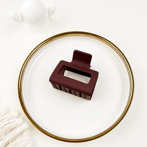 Close-up of matte burgundy square hollow hair claw clip on a white decorative plate