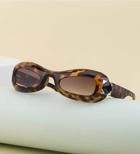 Detail of tortoise oval sunglasses with signature metal T logo and gradient brown lenses