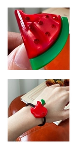 Detailed close-up of a fruit-shaped hair tie with sparkling red rhinestones and elastic band