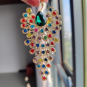 Close-up of gold peacock brooch with multicolored rhinestones and a large green teardrop gem