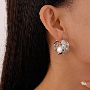 Close-up of silver mesh hollow C-shape hoop earring with an inlaid white pearl detail