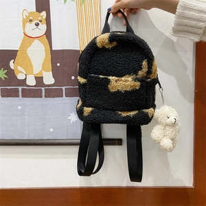 Détail d'un mini sac à dos en polaire sherpa noir et beige avec pendentif ours peluche