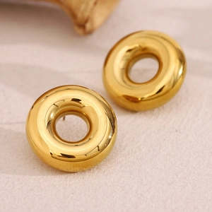 Detailed macro shot of 18K gold-plated stainless steel hollow hoop earrings on fabric