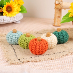 Set of five colorful knitted pumpkins on linen fabric for cozy autumn home decoration