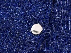 Macro shot of dark blue tweed fabric texture with a polished silver metal button detail