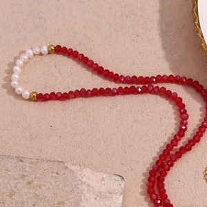 Close-up of red faceted beads and white pearls on a gold-plated beaded necklace