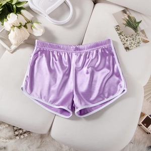 Flat lay of purple satin athletic shorts with white piping on a white leather sofa