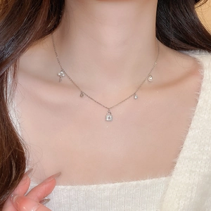 Detailed view of silver charm necklace featuring keys locks and pearls on a model