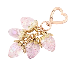 Macro detail of a pink and gold strawberry keychain with sparkling crystal embellishments