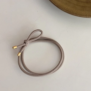 Détail de l'élastique à cheveux taupe avec attache en métal doré poli brillant