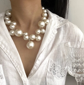 Detail of layered oversized pearl necklace featuring varied sizes and silver ring accents