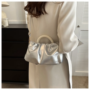 Silver metallic pleated cloud bag with pearl handle worn by model in interior setting
