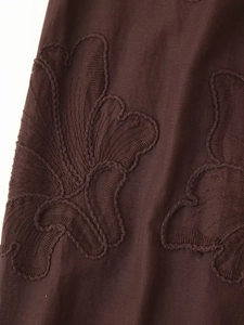 Gros plan détaillé du tissu marron présentant des motifs de broderie florale sophistiqués