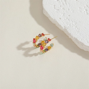 Close-up of colorful heart-shaped zircon earrings on a textured stone display