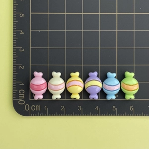Close-up of mini resin candy charms in multiple colors with stripes for DIY crafts