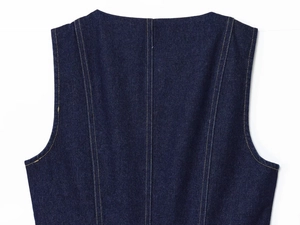 Close-up of dark blue denim vest neckline with contrast yellow stitching and twill texture